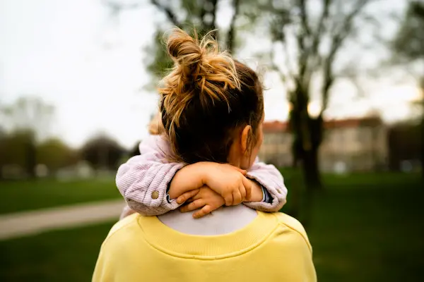 Madre abraza a su hijo en un parque, representando la custodia completa tras un proceso legal de separación o divorcio.