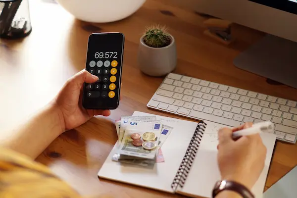 Persona calcula gastos con billetes y monedas sobre la mesa, vinculado a pensión alimenticia y motivos de impago.