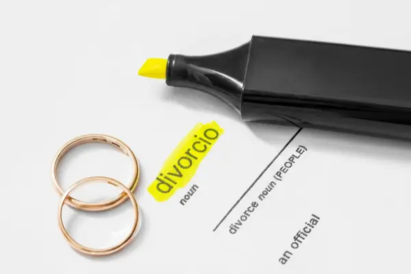 Anillos y subrayador sobre documento con la palabra divorcio, simbolizando pensión compensatoria tras separación matrimonial.