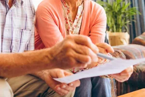 Pareja mayor revisa documentos, representando el derecho a pensión de viudedad tras separación ocurrida hace más de diez años.