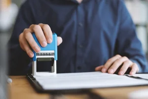 Mano estampando un documento oficial, representando el trámite de empadronamiento de hijos con padres separados.