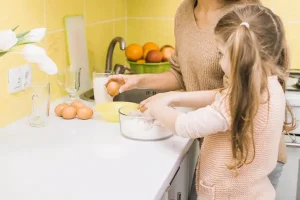Una madre y su hija preparan una receta juntas en la cocina, representando el rol del alimentista en la vida cotidiana.