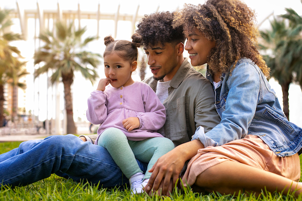 Familia sentada en un parque, con un niño pequeño entre sus padres, representando el proceso de solicitud de nacionalidad española para hijos extranjeros.