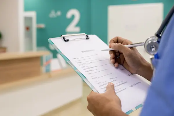 Profesional sanitario escribe en un informe médico, relacionado con casos de negligencia médica documentada.